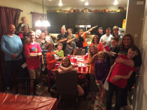A group of adults and kids gathered around a table.
