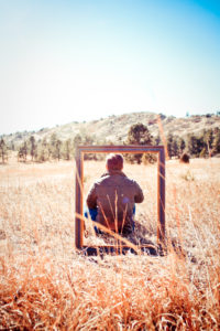 man sitting in field in front of empty frame