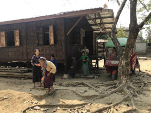 woman gathers wood outside home in Myanmar