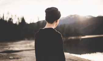 male teenager in beanie facing a lake