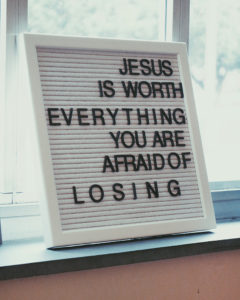 White letter board with black letters that says Jesus is worth everything you are afraid of losing.